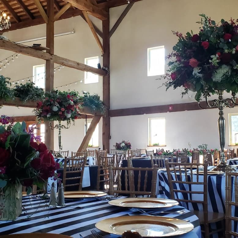 Head table with a black and white striped runner and a tall floral arrangement