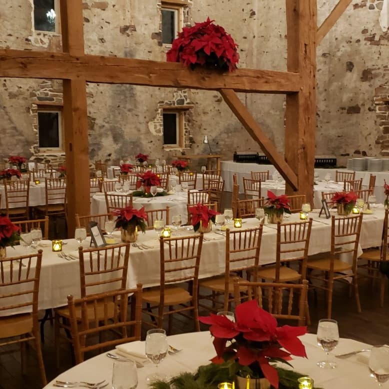 Barn reception tables dressed with red florals for a holiday event