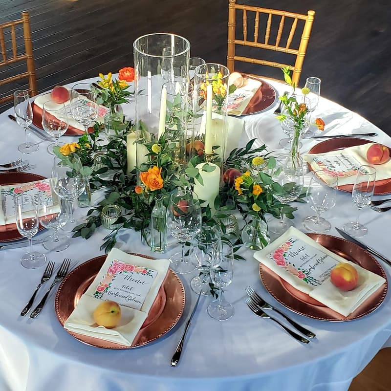Round table with gold chargers, a floral centerpiece and favor bags at each seat