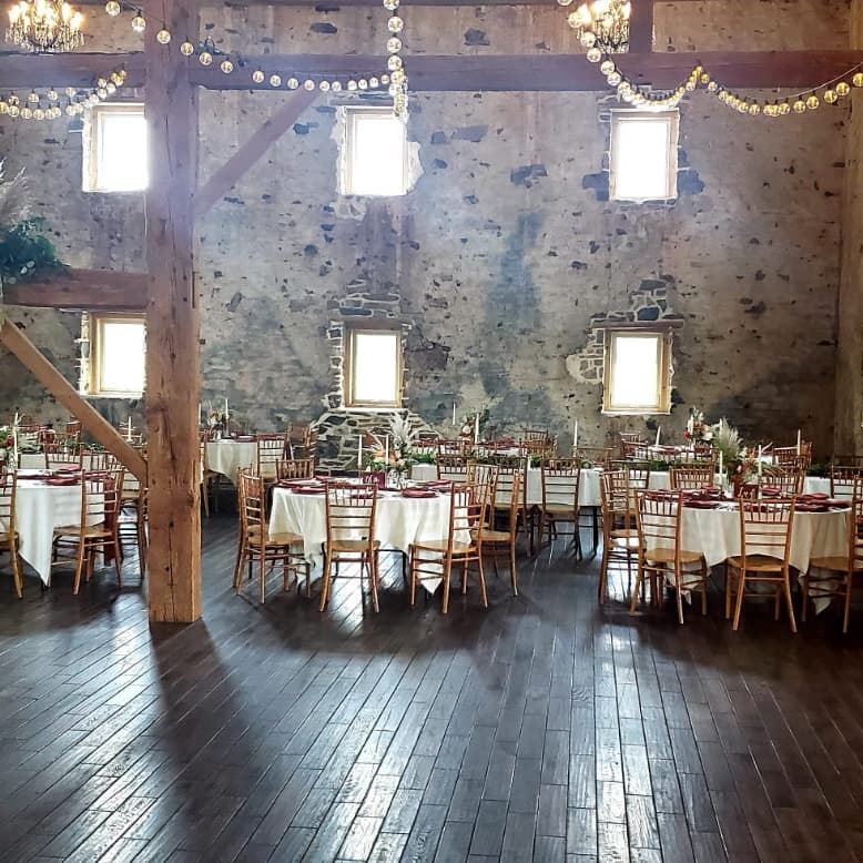 Sunlit stone barn set for a seated dinner with white linens