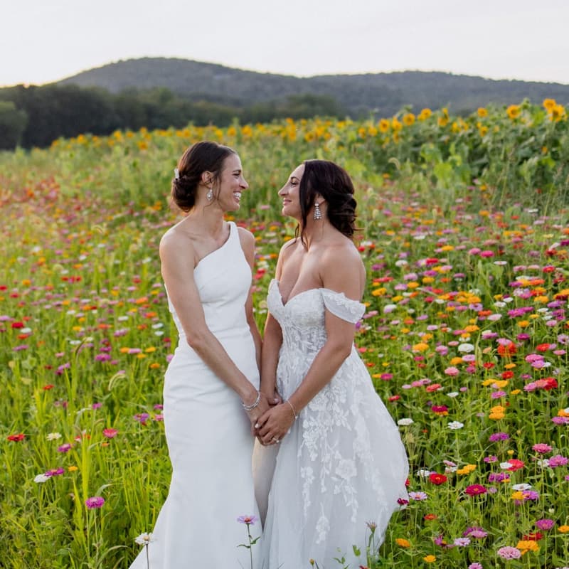 Two brides holding hands in a wildflower field