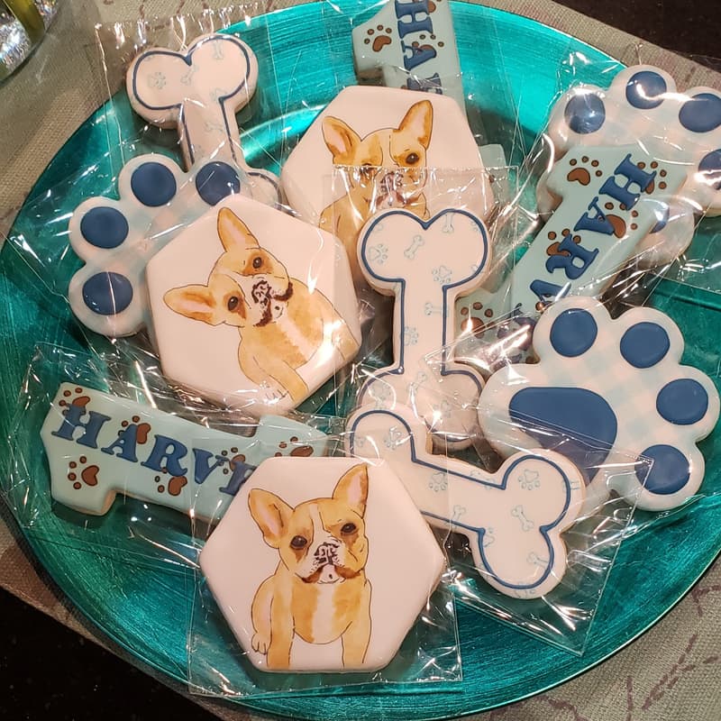 Dog-themed decorated sugar cookies arranged on a teal plate